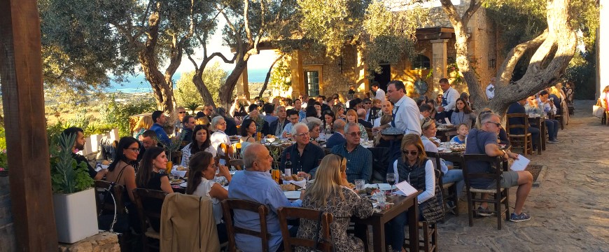 many people eating together at long tables outdoors at Agreco Farms 