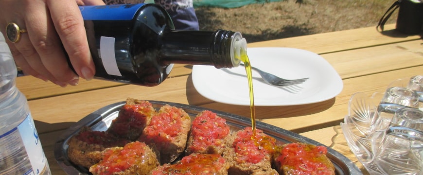 olive oil being poured onto crushed tomato on rusks 