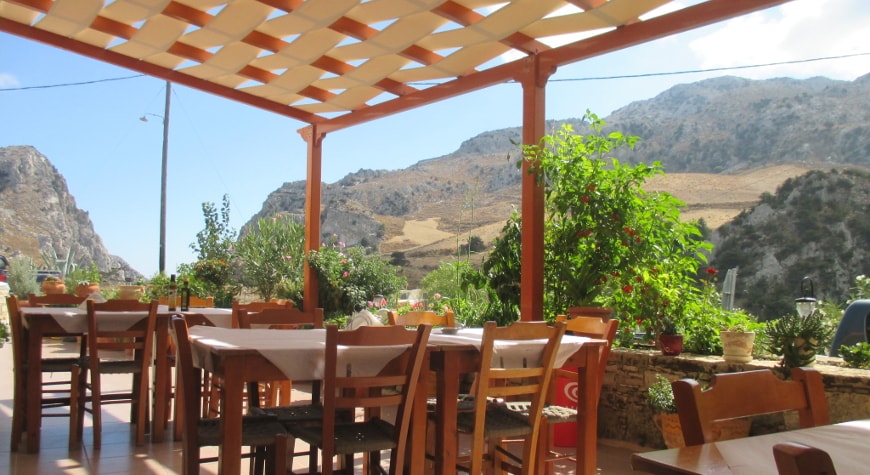 Tables, plants, and view of hills and sky at Iliomanolis Taverna
