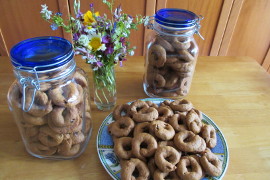 Olive oil orange juice cookies on a plate and in two glass jars near a glass of flowers