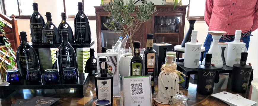 several bottles of olive oil from three different brands on display on a table