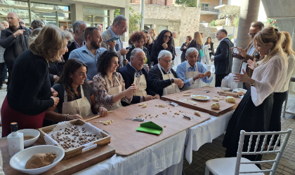 participants sitting at a table and standing behind it for a pasta making workshop