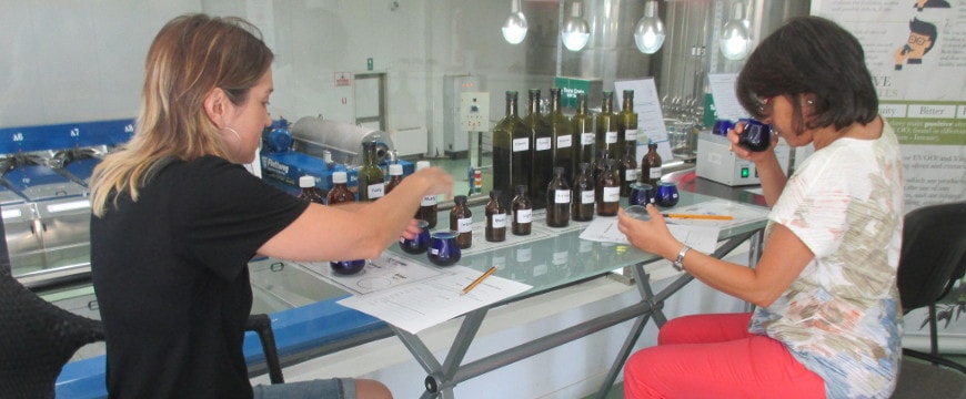 Two women smelling and tasting olive oil at a tasting seminar